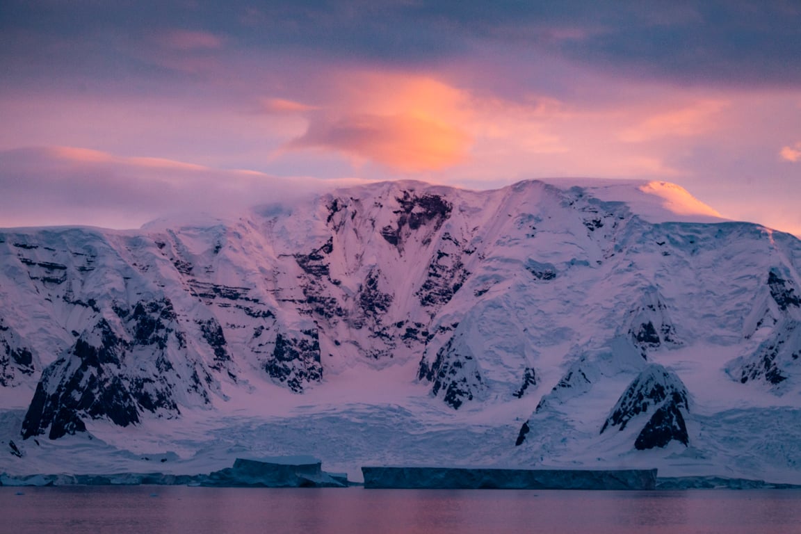 Dramatic sunset over Antarctic mountains and icebergs at Neko Harbour with changing weather